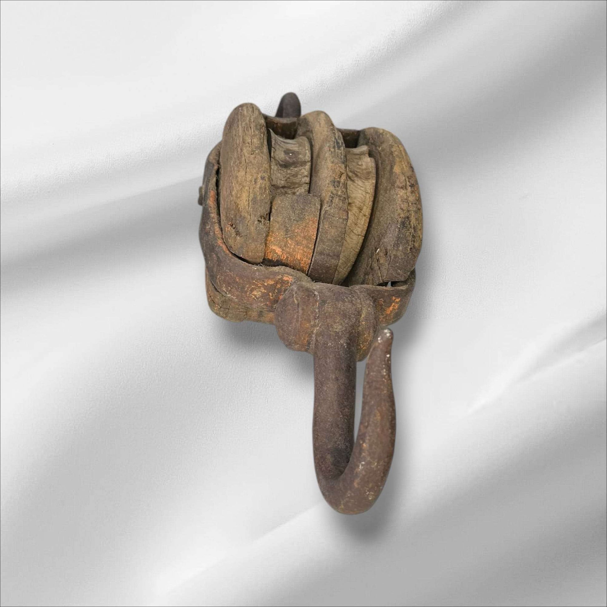 La polea doble antigua de madera y hierro es una pieza auténtica de ingeniería tradicional, utilizada en barcos y talleres para elevar cargas pesadas con mínima fuerza. Este aparejo de poleas combina la robustez del hierro forjado con la nobleza de la madera envejecida, mostrando el arte del trabajo manual y la precisión funcional de otra época.

Su estructura, compuesta por dos roldanas de madera maciza encajadas en un cuerpo sólido, permite una distribución equilibrada del peso y una operación suave. Cada