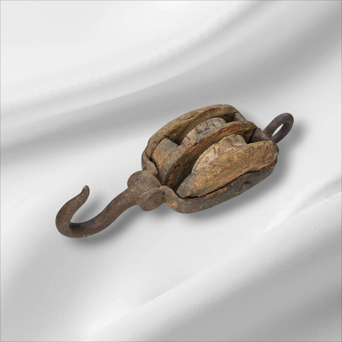 La polea doble antigua de madera y hierro es una pieza auténtica de ingeniería tradicional, utilizada en barcos y talleres para elevar cargas pesadas con mínima fuerza. Este aparejo de poleas combina la robustez del hierro forjado con la nobleza de la madera envejecida, mostrando el arte del trabajo manual y la precisión funcional de otra época.

Su estructura, compuesta por dos roldanas de madera maciza encajadas en un cuerpo sólido, permite una distribución equilibrada del peso y una operación suave. Cada