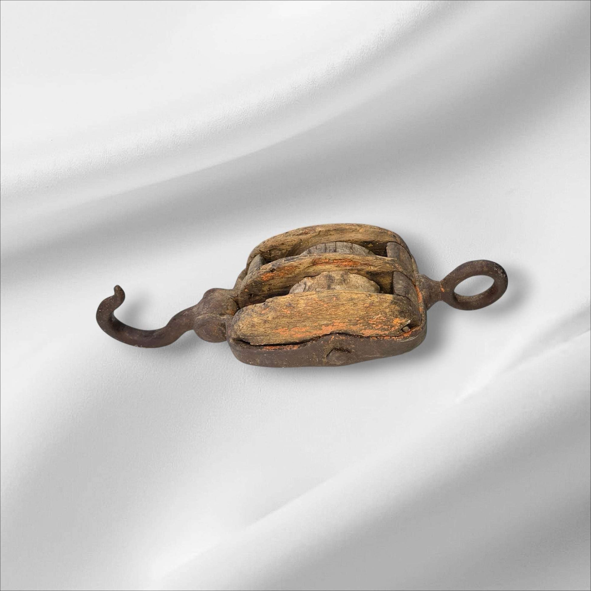 La polea doble antigua de madera y hierro es una pieza auténtica de ingeniería tradicional, utilizada en barcos y talleres para elevar cargas pesadas con mínima fuerza. Este aparejo de poleas combina la robustez del hierro forjado con la nobleza de la madera envejecida, mostrando el arte del trabajo manual y la precisión funcional de otra época.

Su estructura, compuesta por dos roldanas de madera maciza encajadas en un cuerpo sólido, permite una distribución equilibrada del peso y una operación suave. Cada