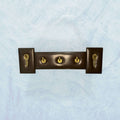 Perchero elegante de metal y cuero exclusivo y único con cuatro ganchos dorados sobre base marrón oscura. Ideal para decoración de interiores con estilo.