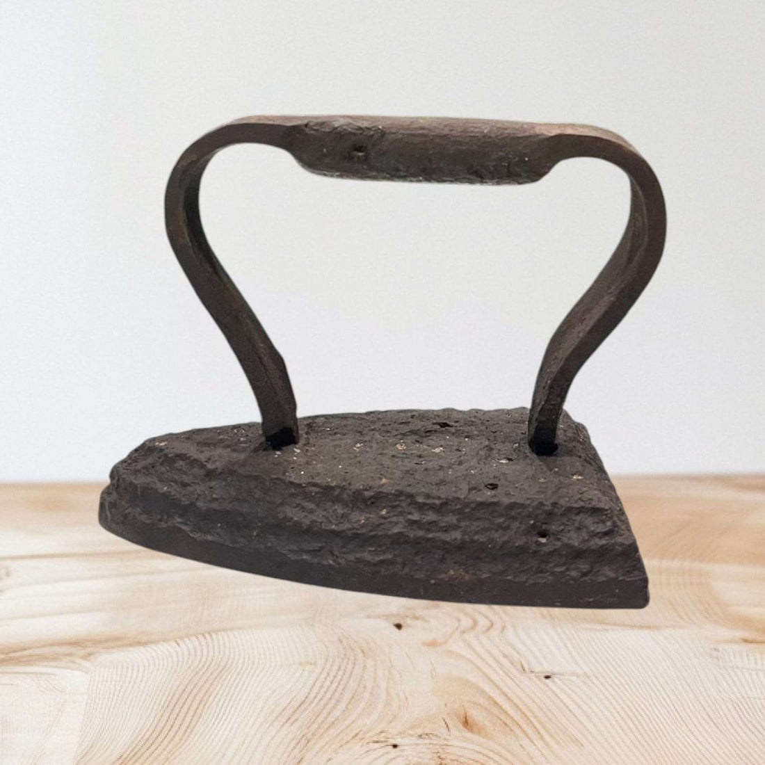 Plancha antigua de hierro fundido con mango curvo, ideal para decoración vintage en hogar o colección histórica.