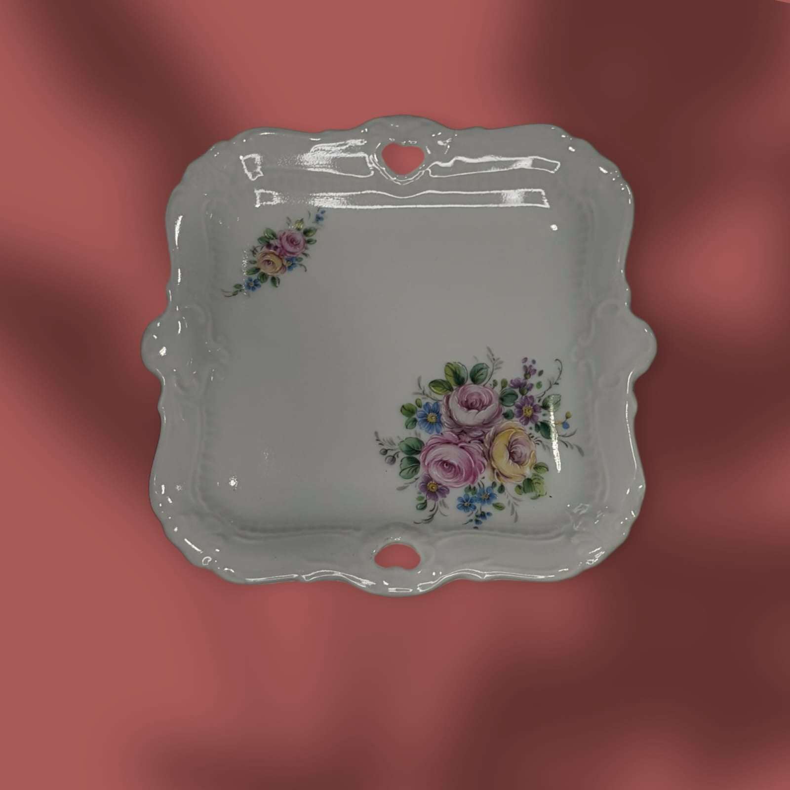 Vista lateral de bandeja de porcelana con relieve y perforaciones decorativas.