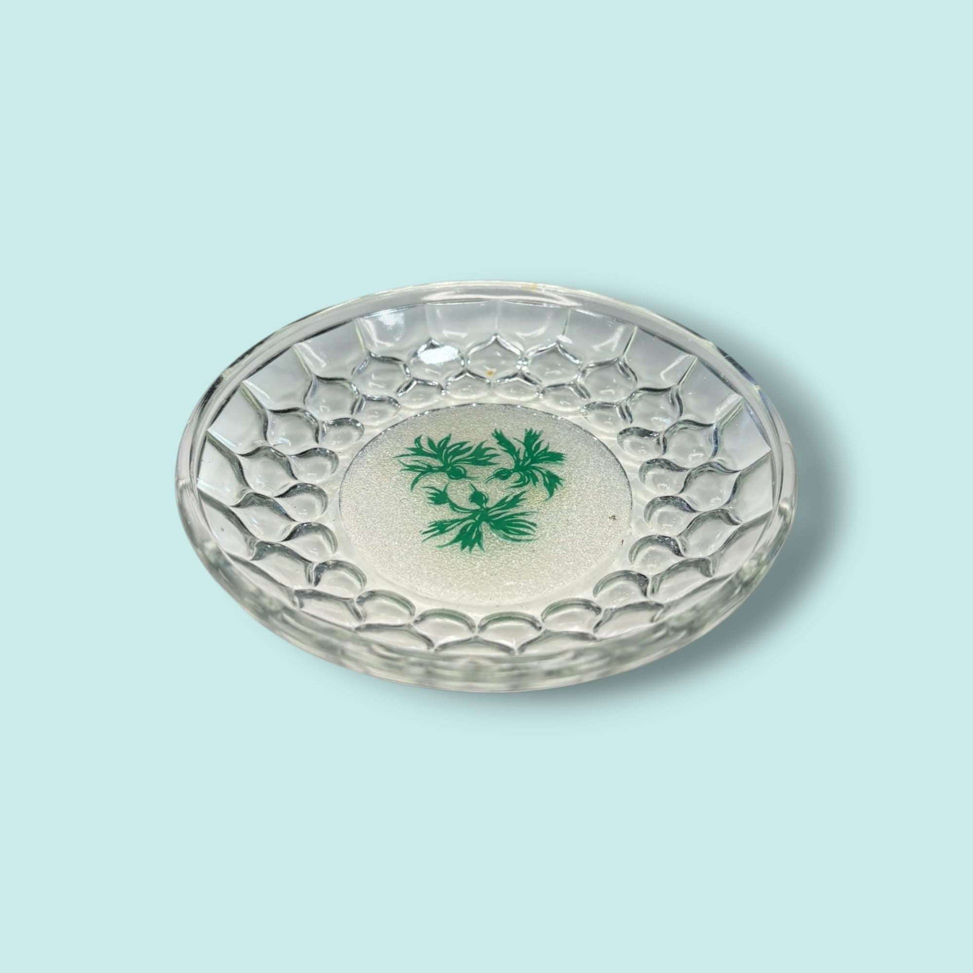 Plato pequeño de cristal para canapés con diseño en relieve tipo panal y motivo vegetal verde en el centro. Perfecto para aperitivos elegantes.