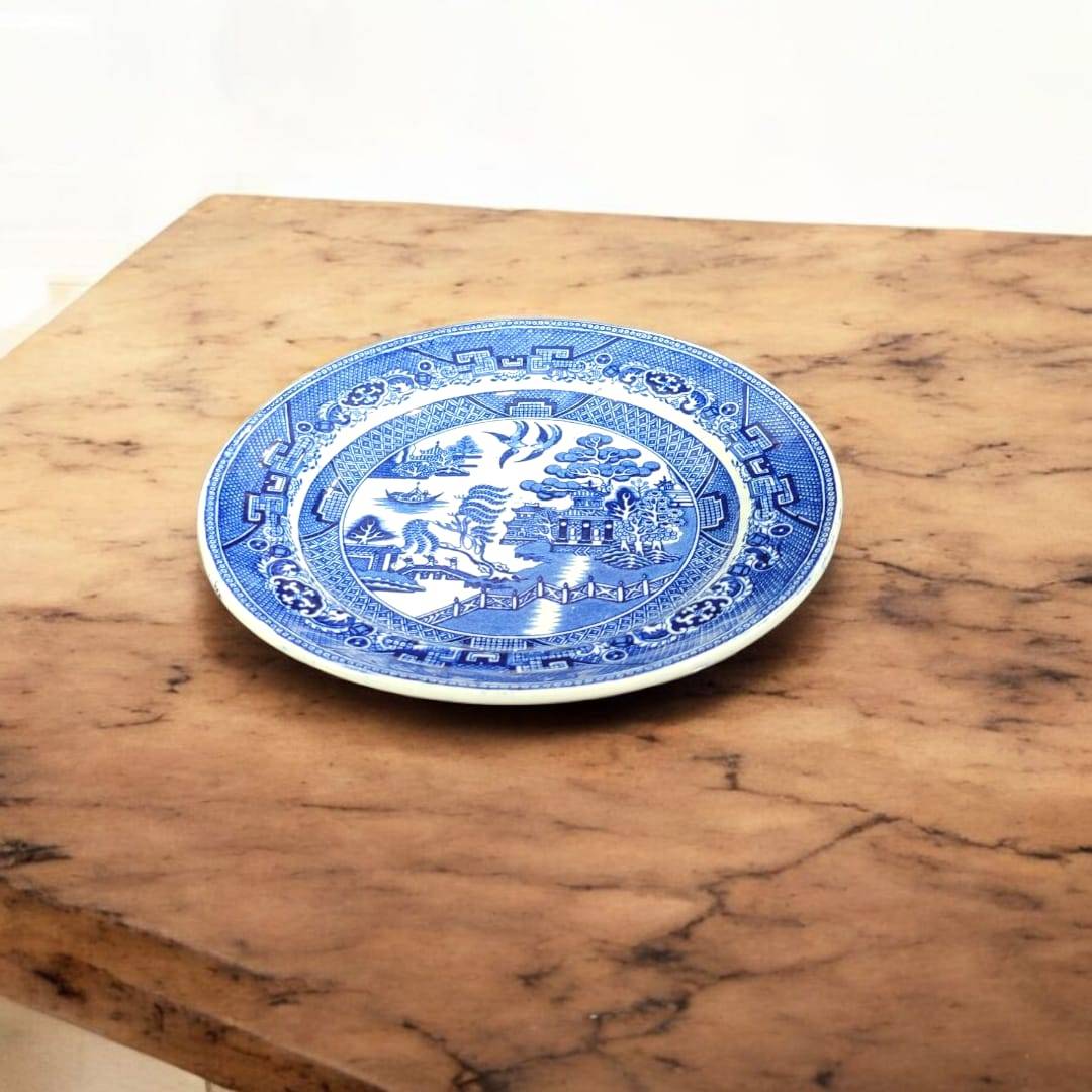 Plato Willow porcelana inglesa antigua con diseño azul clásico sobre mesa de mármol. Ideal para decoración vintage en hogar y jardín.