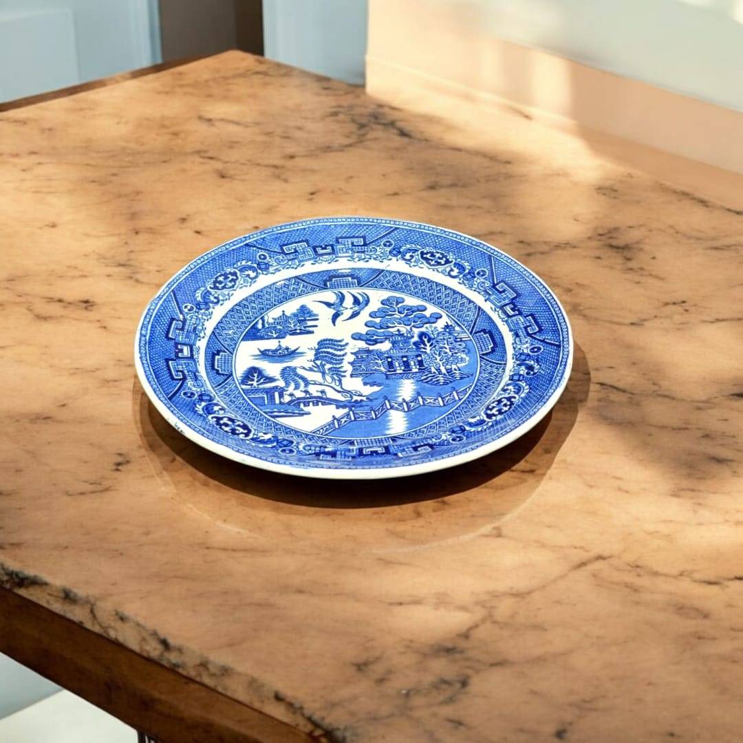 Plato Willow porcelana inglesa antigua con diseño azul clásico sobre mesa de mármol. Ideal para decoración vintage en hogar y jardín.