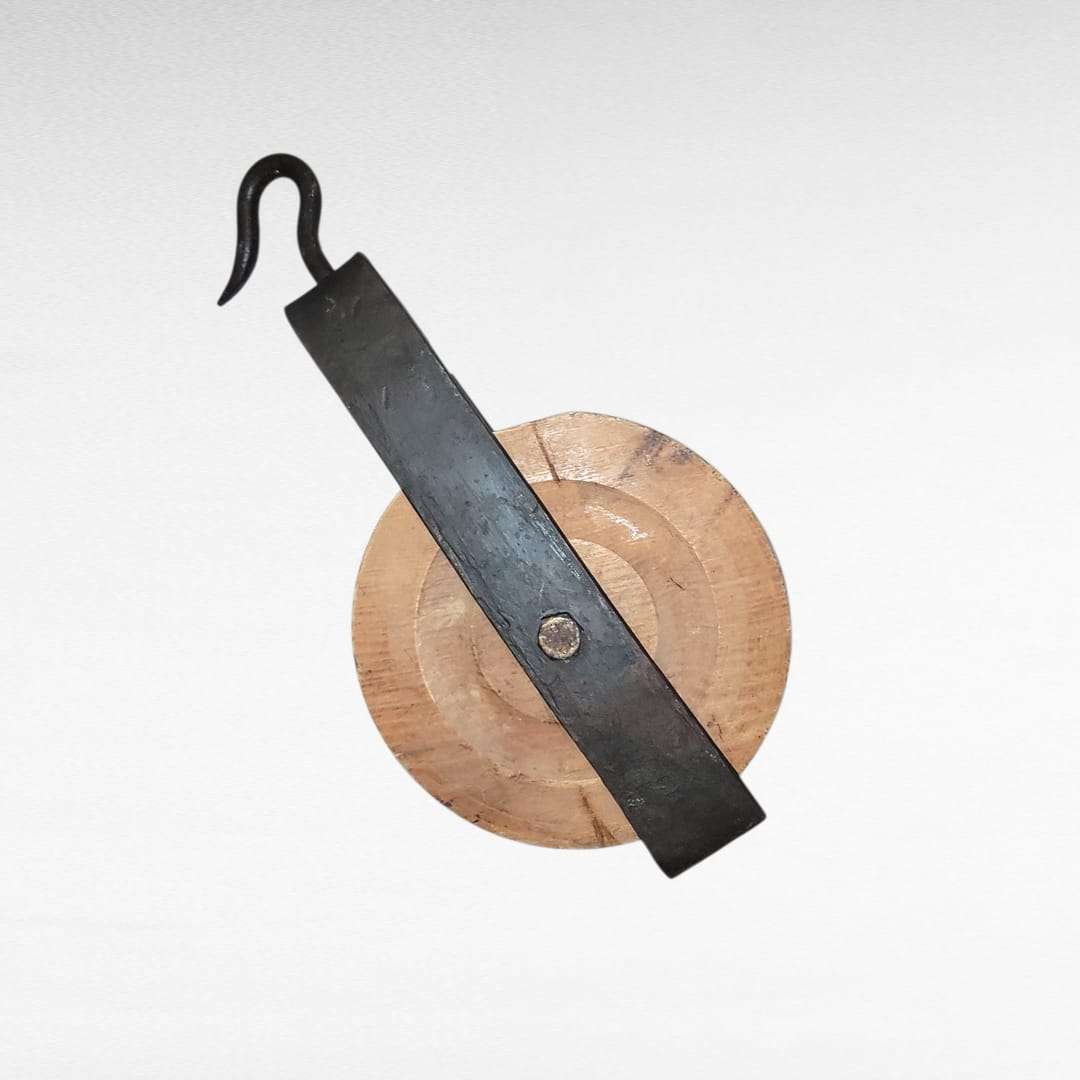 Polea antigua con rueda de madera torneada y estructura de forja con gancho