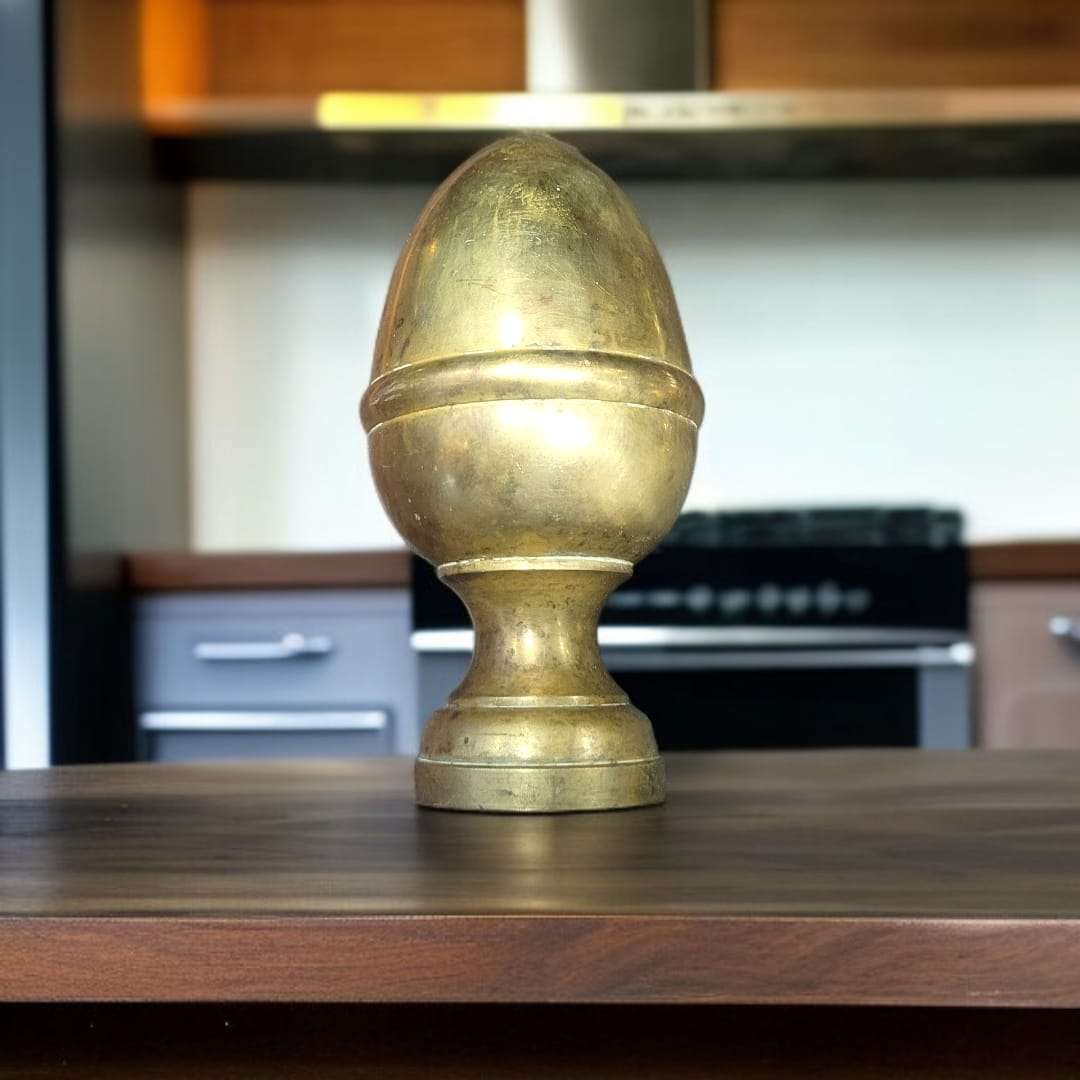 Remate de bronce tipo piña tumbado sobre superficie de madera