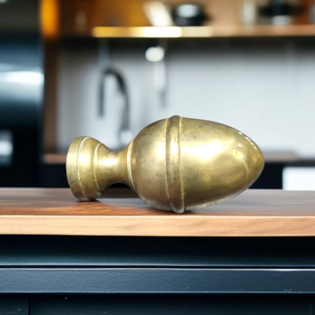 Remate de bronce tipo piña tumbado sobre superficie de madera