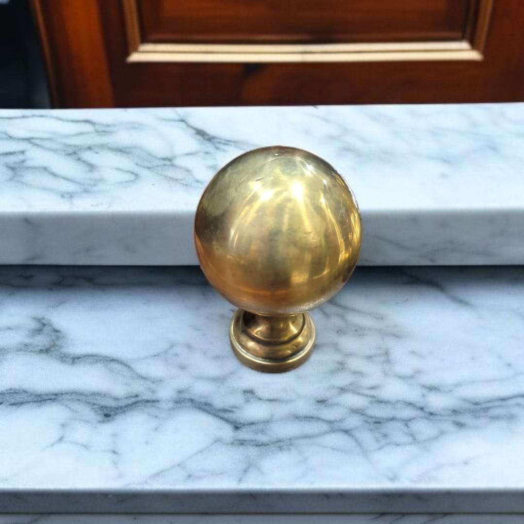 Remate de bronce esférico sobre superficie de mármol blanco