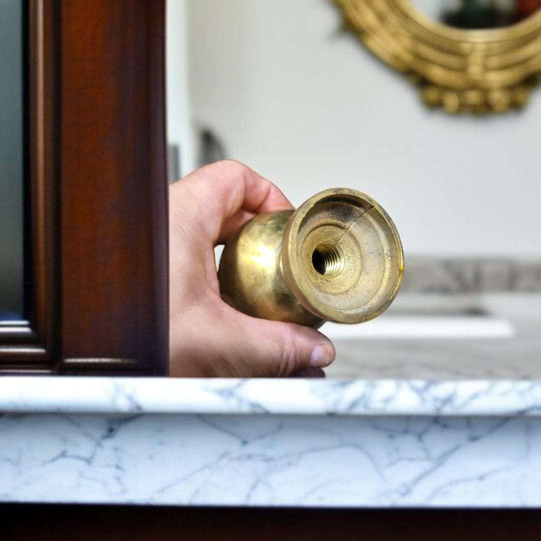 Remate de bronce esférico sobre superficie de mármol blanco