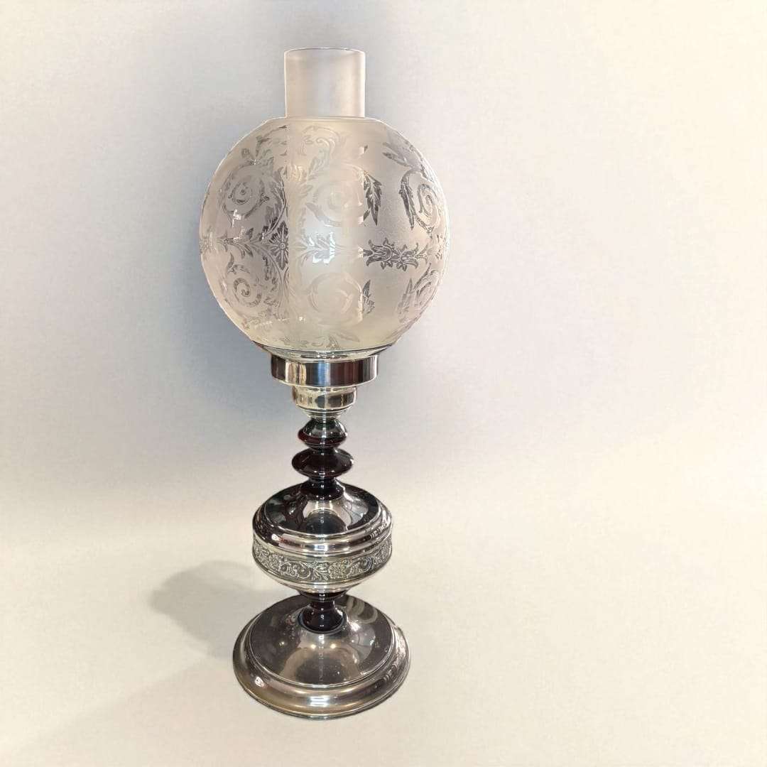 Lámpara de sobremesa tipo quinqué encendida con luz cálida.