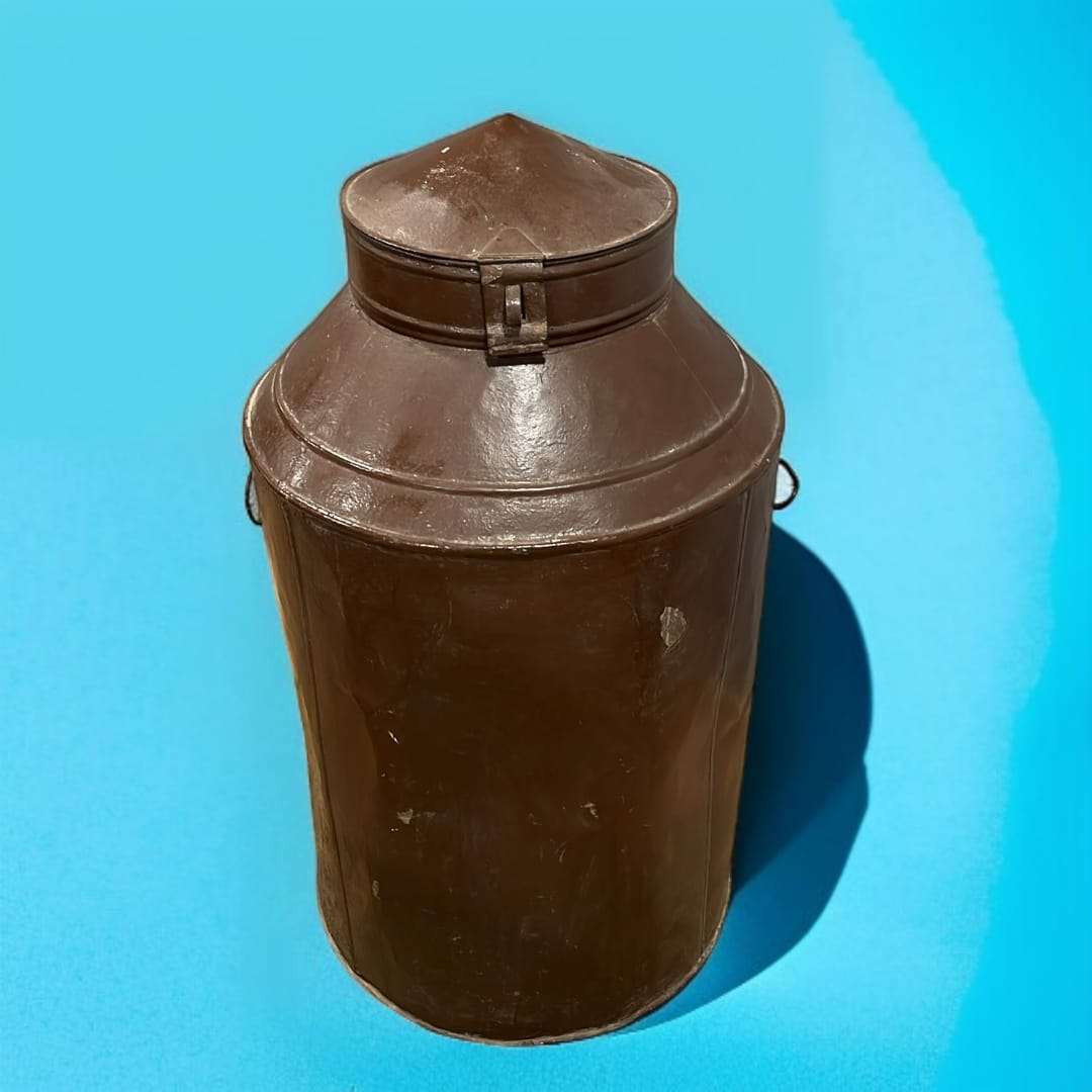 Vista completa de la cántara de chapa sobre fondo azul.