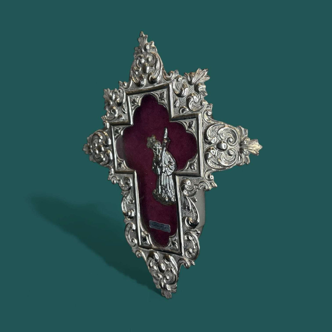 Relicario Cristo del Gran Poder en plata de ley sobre fondo burdeos.