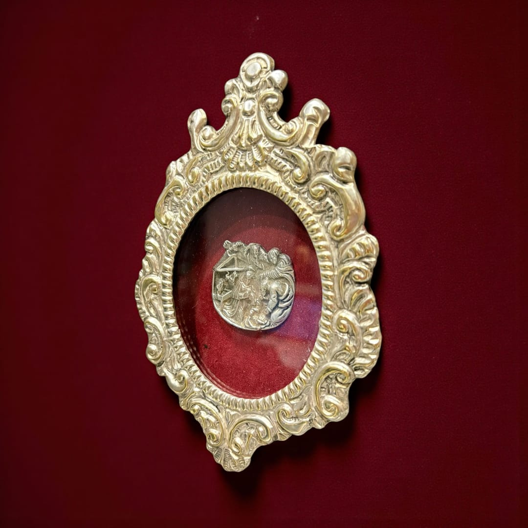 Su interior, protegido por cristal, guarda una escena minuciosamente labrada en plata, representando el Nacimiento de Cristo: la Virgen María, San José, el Niño Jesús en el pesebre y figuras angelicales que lo envuelven en una atmósfera celestial.