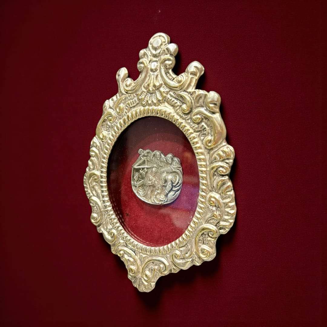 Su interior, protegido por cristal, guarda una escena minuciosamente labrada en plata, representando el Nacimiento de Cristo: la Virgen María, San José, el Niño Jesús en el pesebre y figuras angelicales que lo envuelven en una atmósfera celestial.