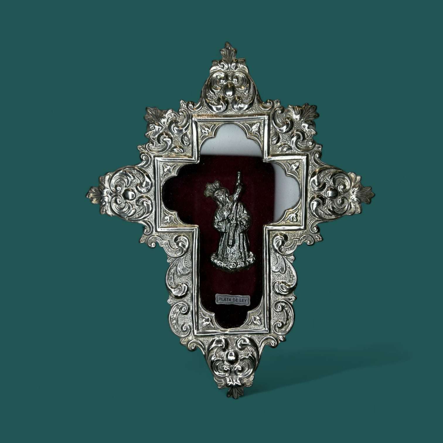 Relicario Cristo del Gran Poder en plata de ley sobre fondo burdeos.