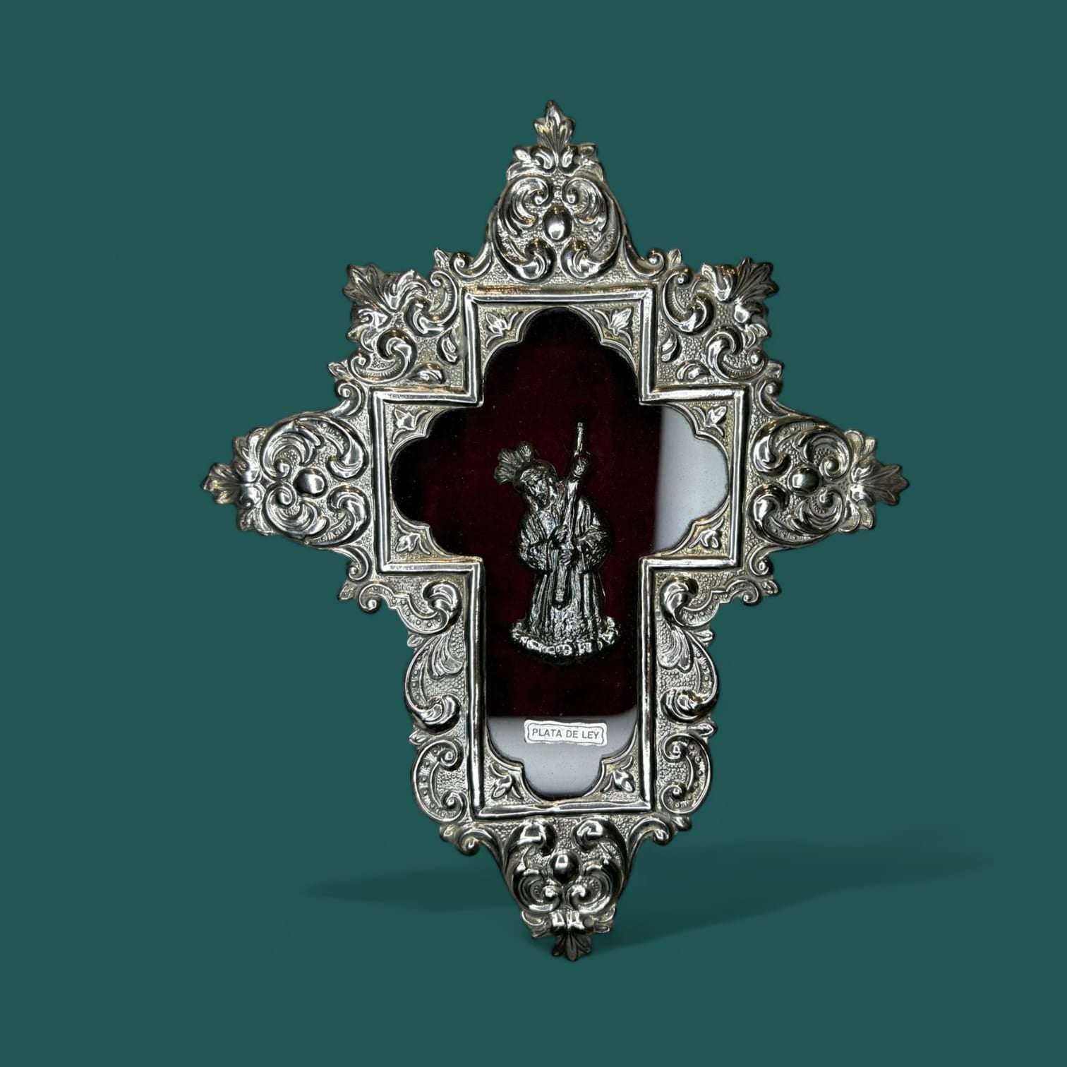 Relicario Cristo del Gran Poder en plata de ley sobre fondo burdeos.