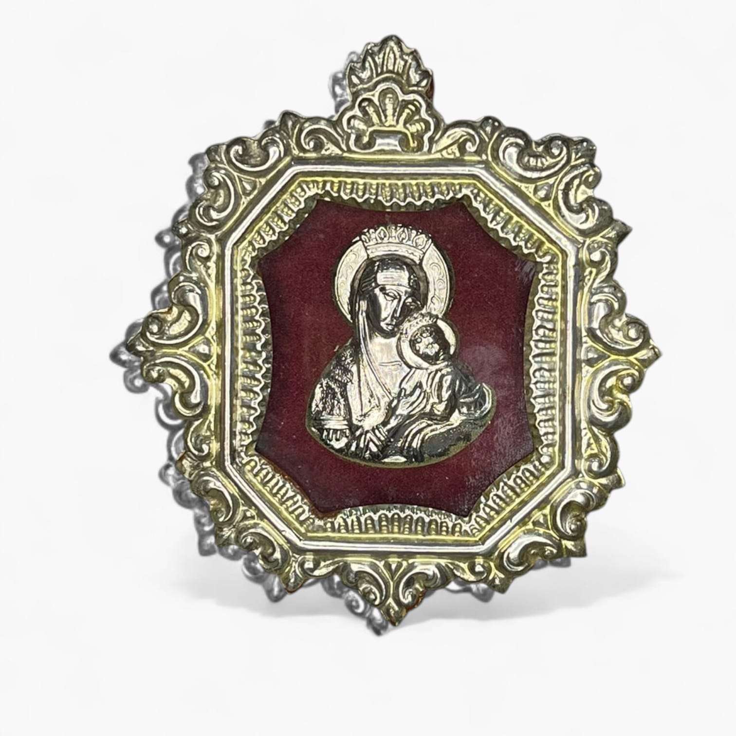 Relicario Virgen con Niño en marco de metal plateado y fondo burdeos.