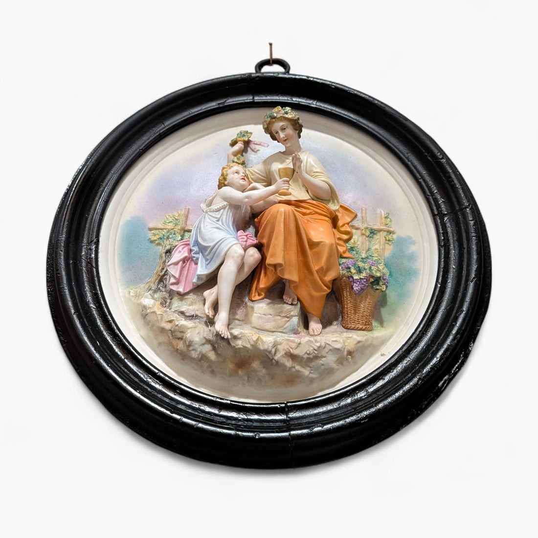 Relieve de porcelana antiguo restaurado escena figurativa con marco negro circular. Decoración clásica para pared en estilo romántico.