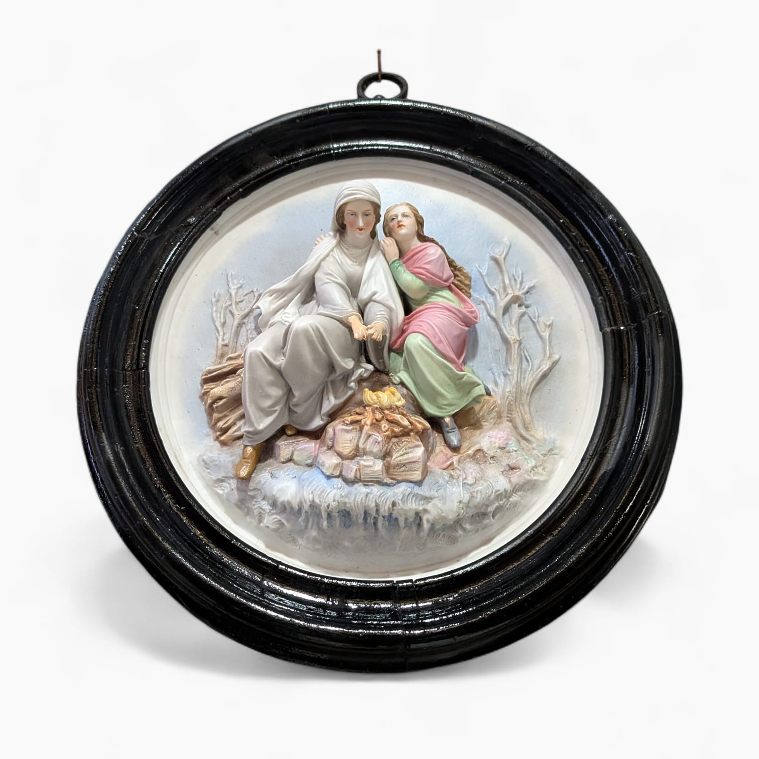 Obra decorativa clásica en porcelana con relieve de dos personajes junto al fuego, en marco negro ovalado, ideal para decoración de interiores.