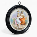 Obra decorativa clásica en porcelana con escena figurativa restaurada, marco negro redondo y detalles florales. Ideal para decoración elegante.