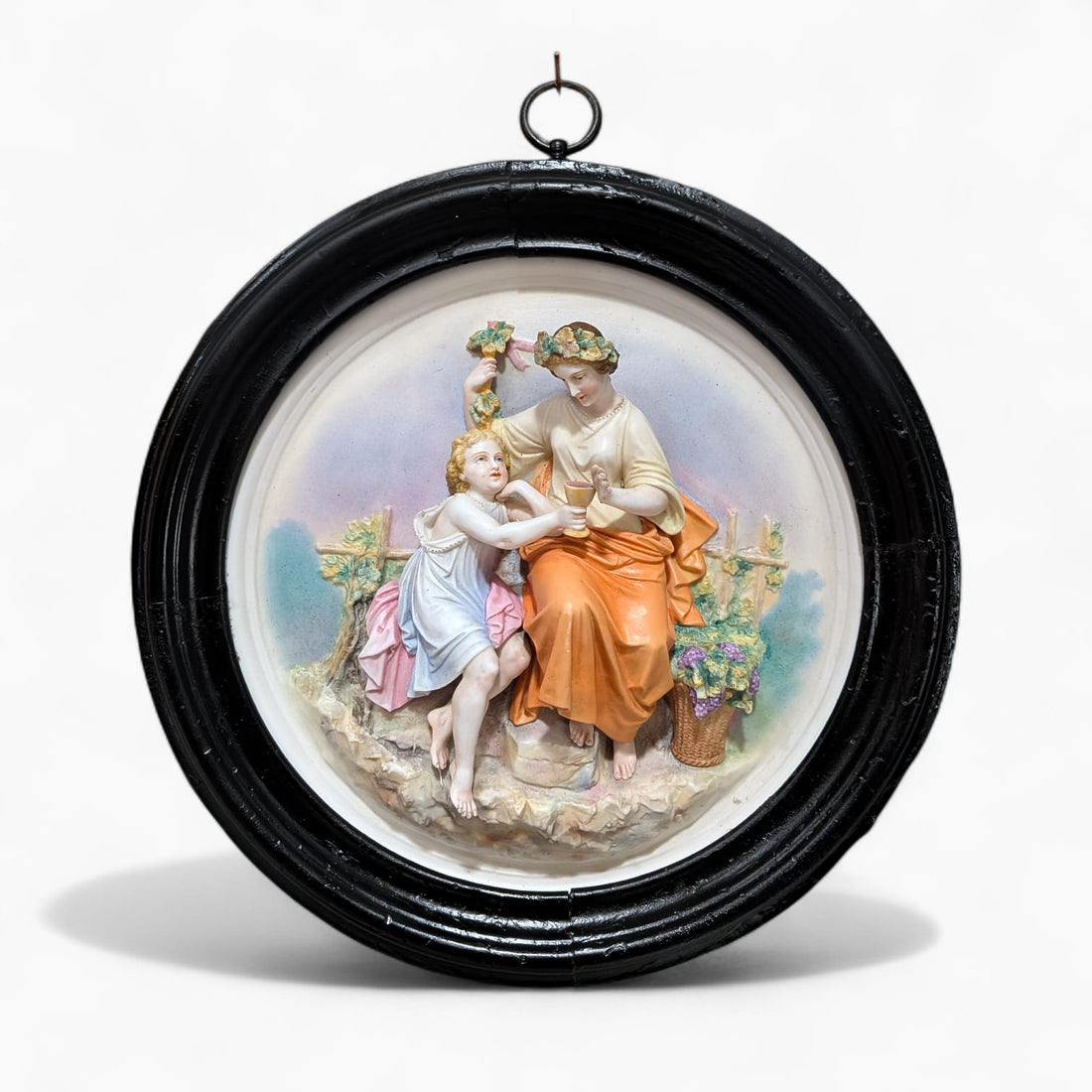 Relieve de porcelana antiguo restaurado escena figurativa con marco negro circular. Decoración clásica para pared en estilo romántico.