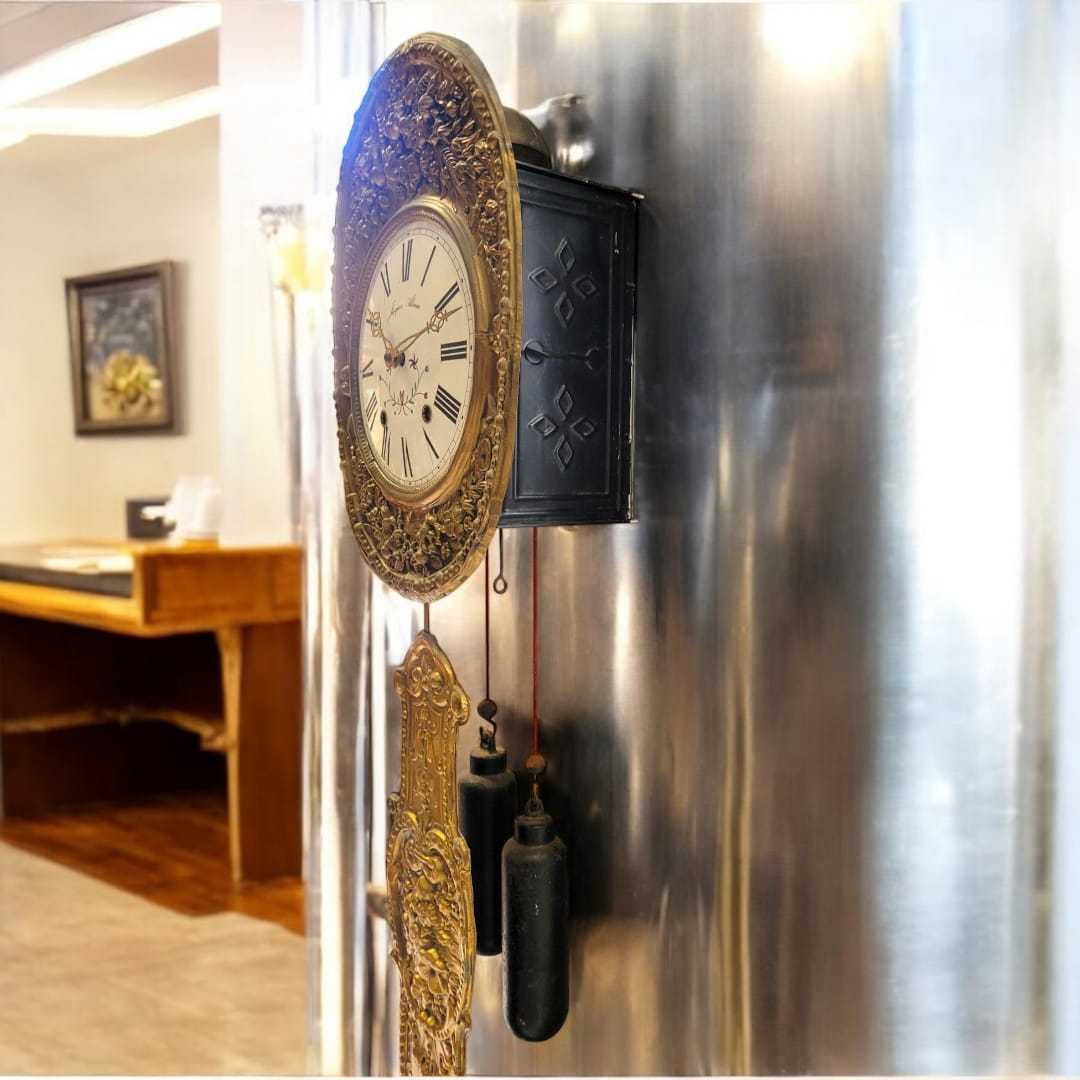 Reloj Comtoise con fondo azul, destacando su estructura en latón repujado y la sofisticación de su diseño clásico.