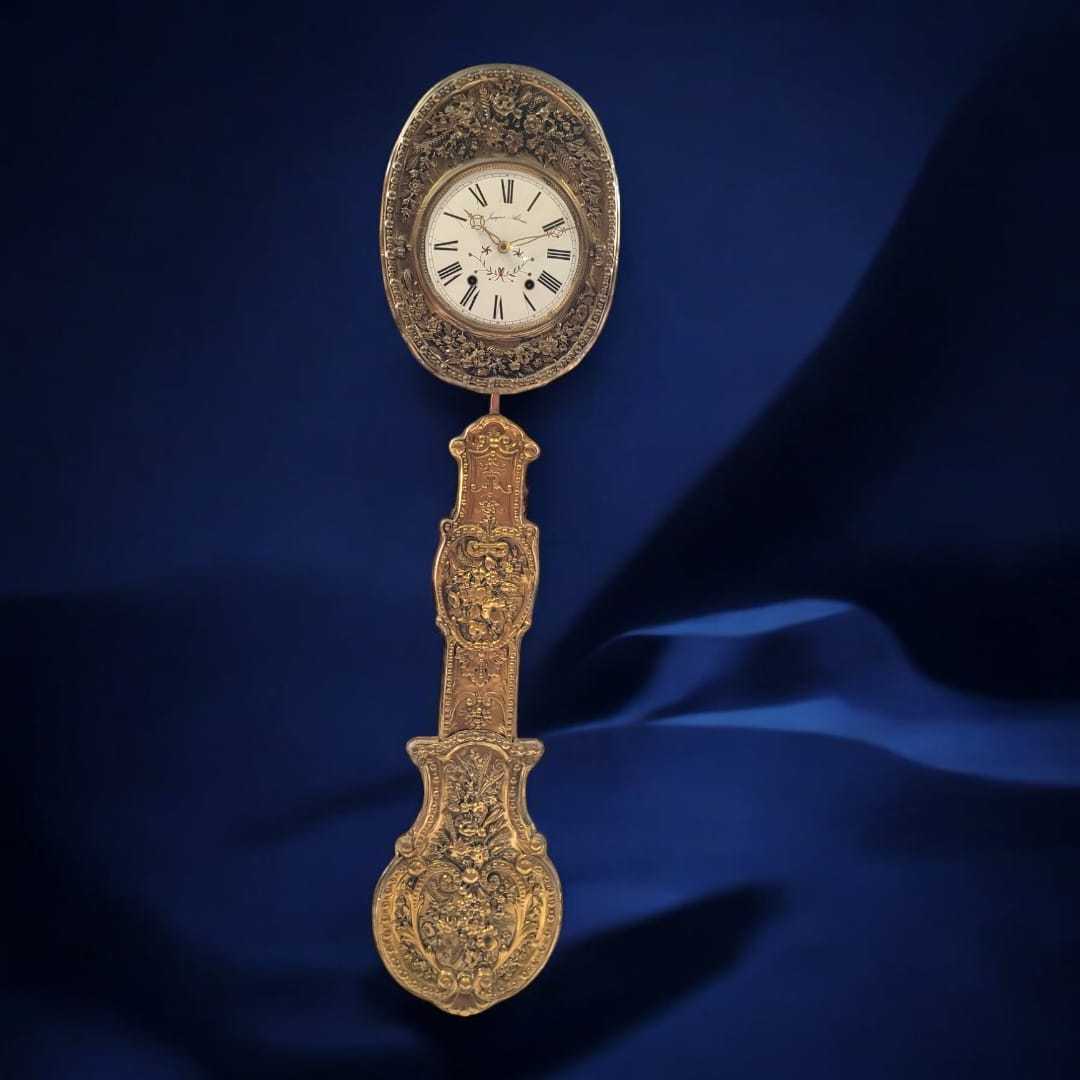 Reloj Comtoise con fondo azul, destacando su estructura en latón repujado y la sofisticación de su diseño clásico.