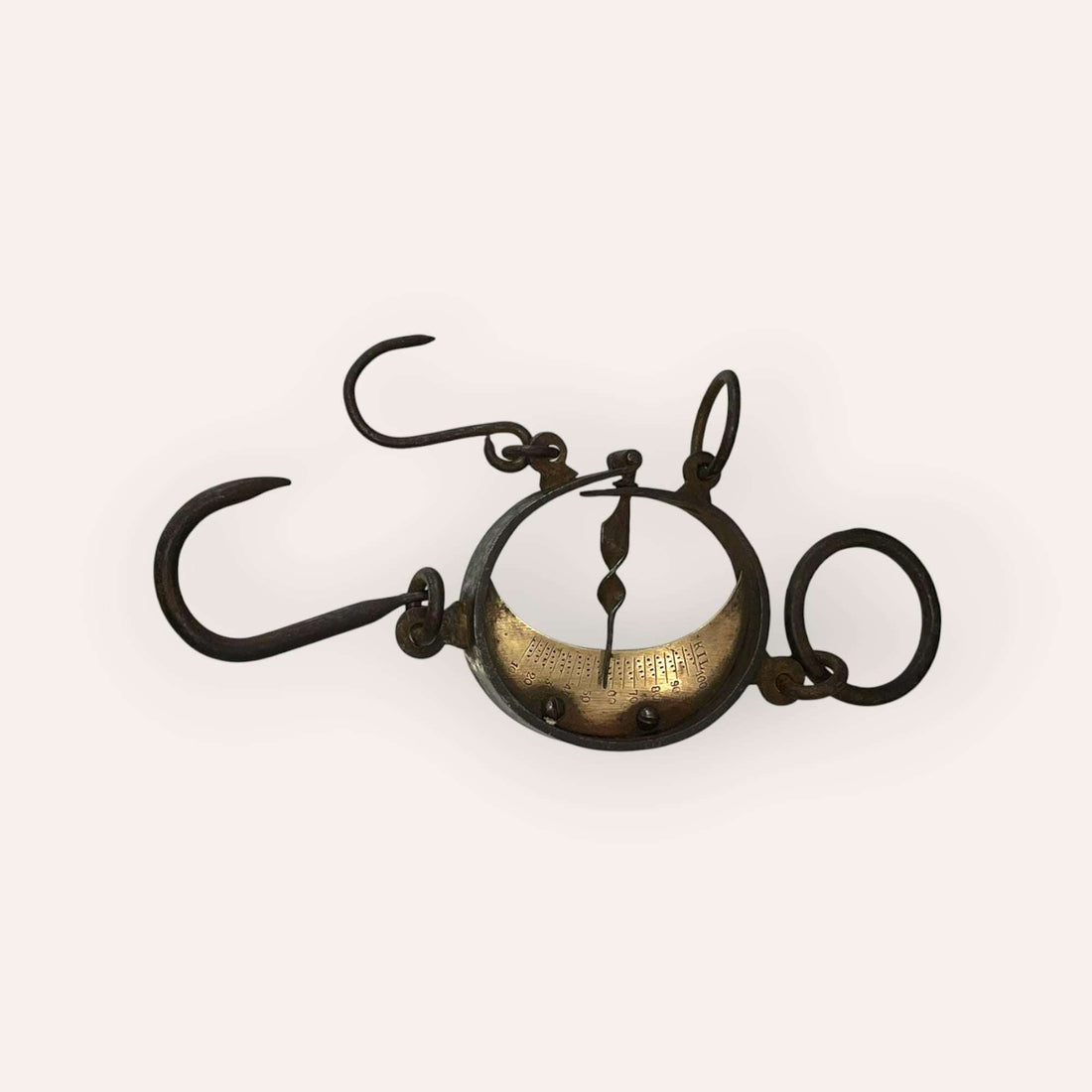 Romana trapera en media luna antigua de hierro y latón, vista frontal.