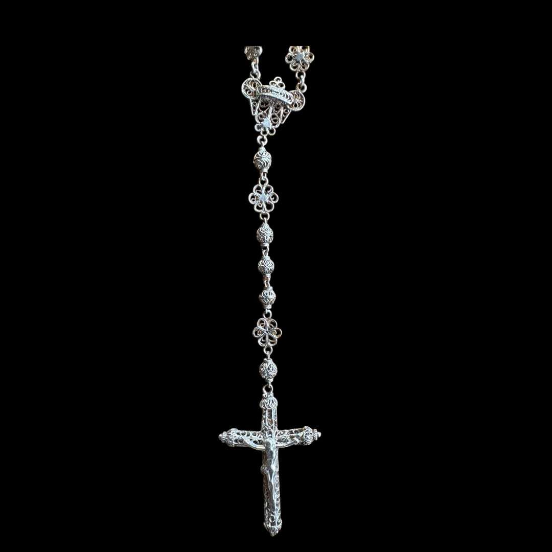 Rosario de plata filigrana con cruz tallada en detalle.