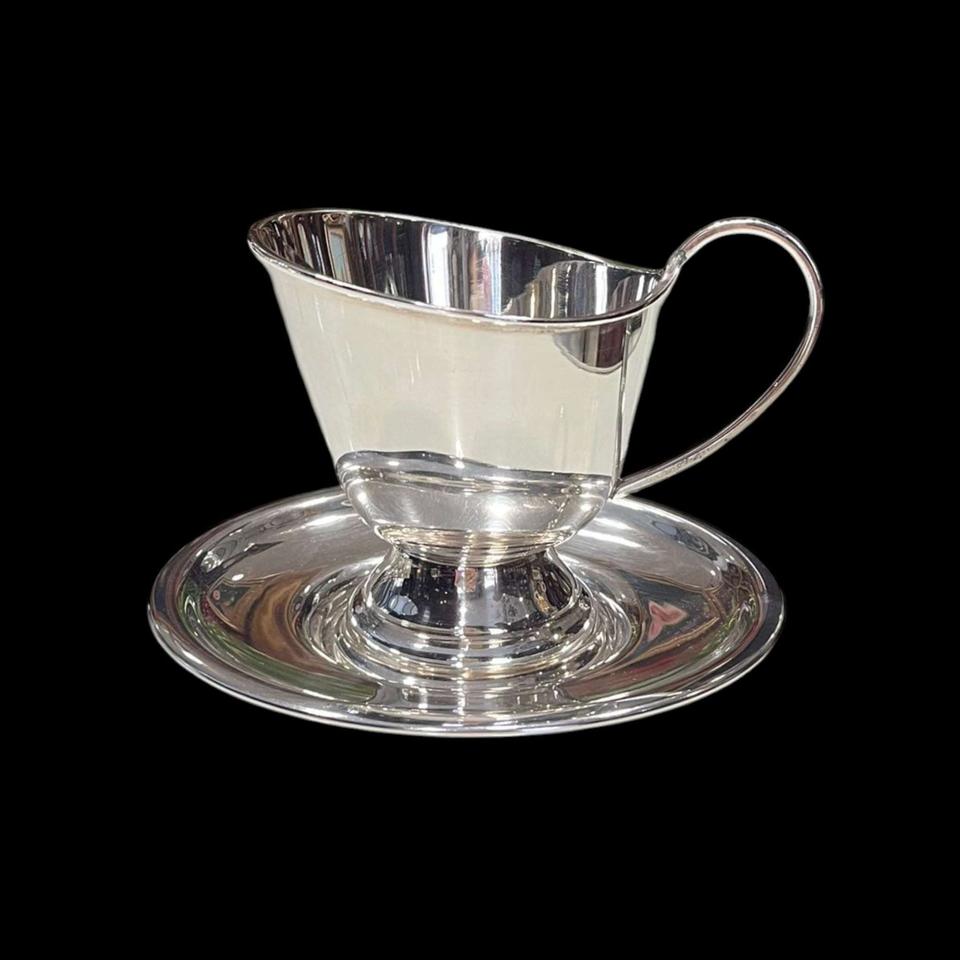 Vista frontal de la Salsera de metal plateado sobre su platillo.