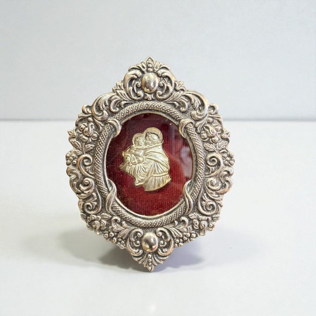 Relicario de plata con San Antonio sobre fondo de terciopelo rojo.