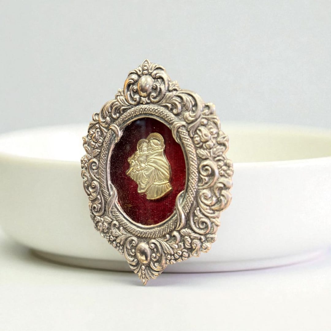 Relicario de plata con San Antonio sobre fondo de terciopelo rojo.