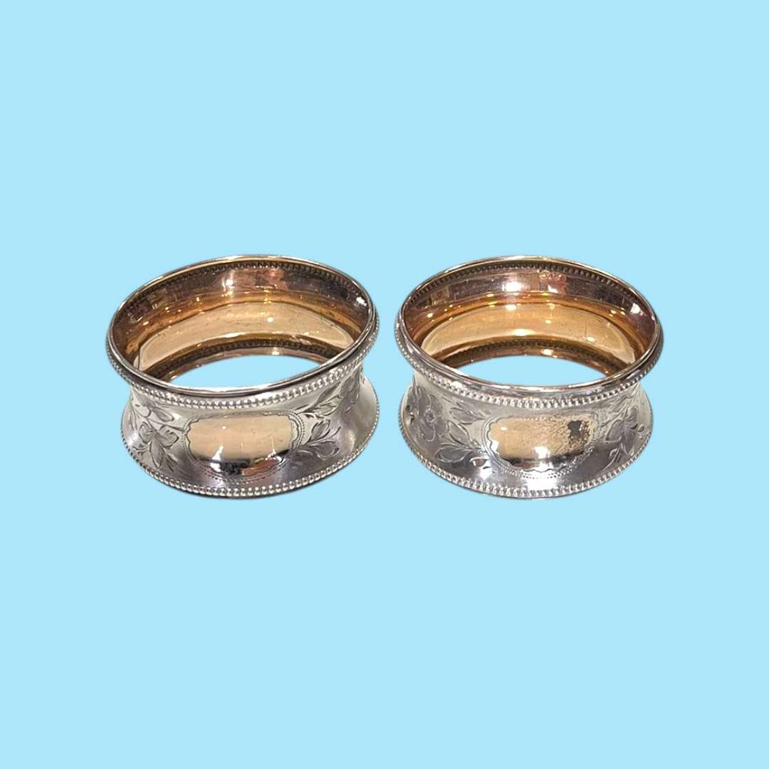 Detalle de servilleteros plateados con borde perla en relieve.