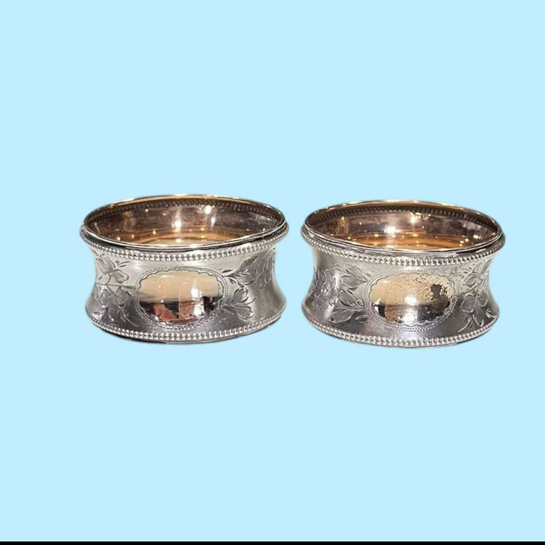 Servilleteros de metal plateado colocados sobre servilletas marrón.