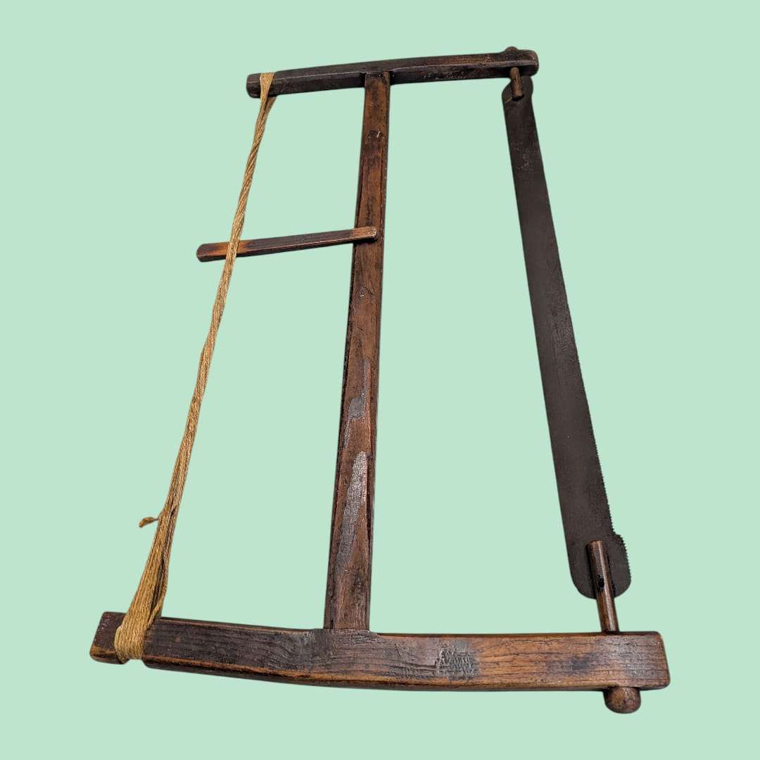 Sierra de arco manual antigua de madera con cuerda de tensión, herramienta original de carpintería ideal para decoración rústica en hogar y jardín.