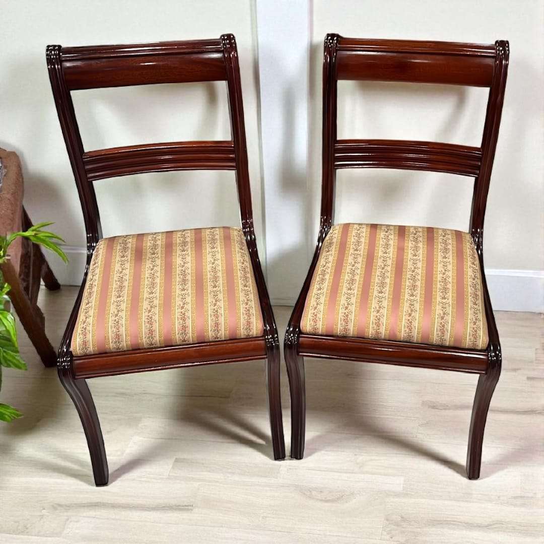 Par de sillas de caoba con tapizado rayado sobre suelo claro.