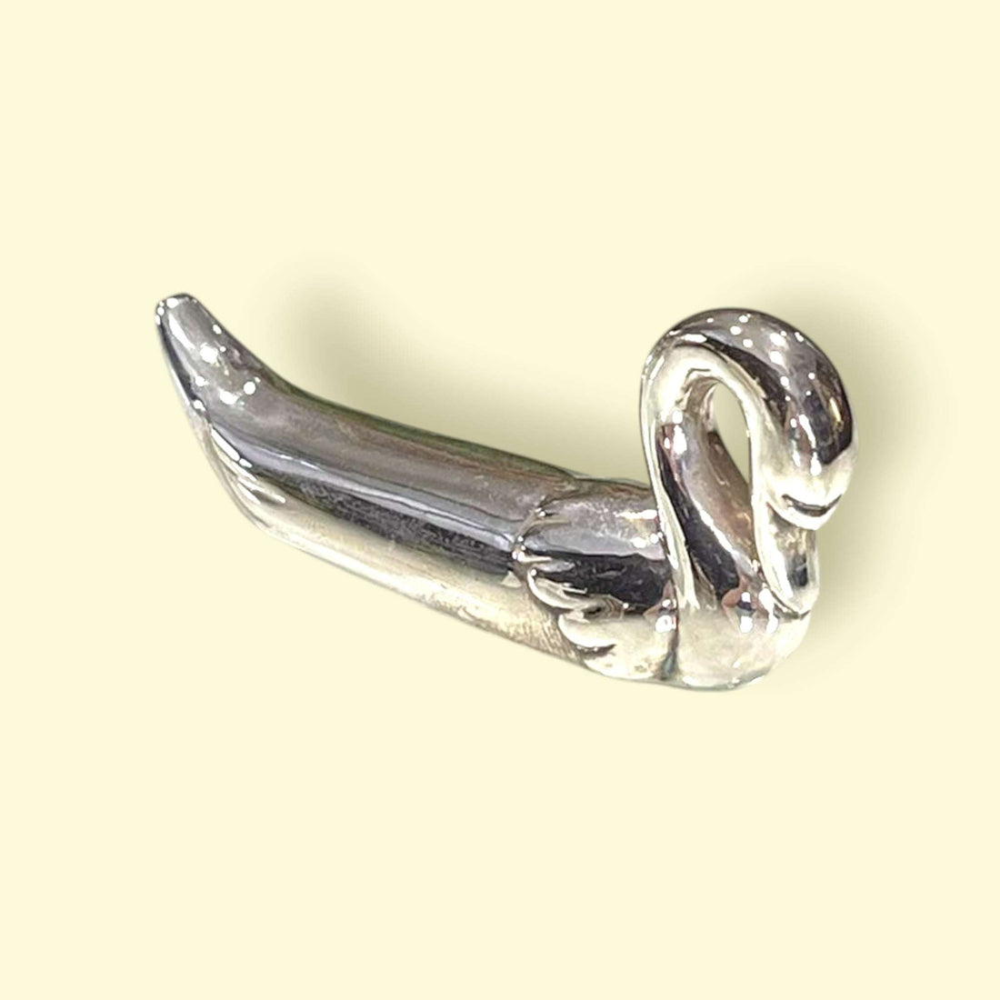 Reposa cubiertos de metal plateado en forma de cisne, vista frontal.