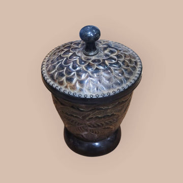 Tibor de metal con relieves vegetales y tapa decorada con patrón floral, ideal para decoración de interiores en estilo rústico o vintage.