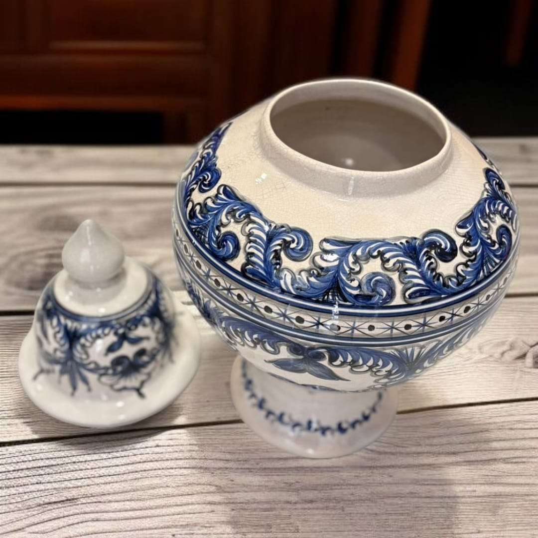 Tibor de cerámica esmaltada azul con diseño floral clásico sobre mesa de madera. Decoración elegante para interiores tradicionales o modernos.