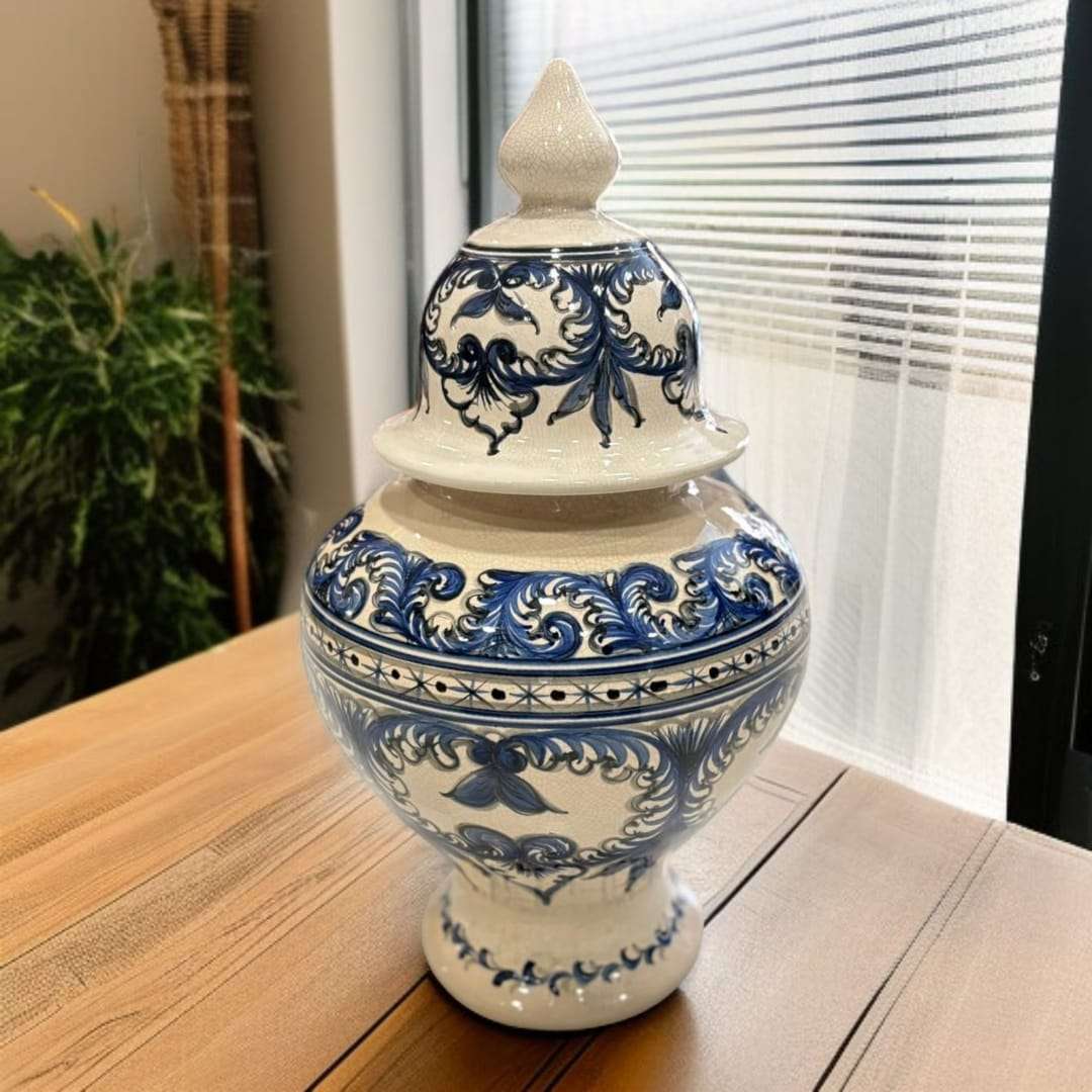Tibor de cerámica esmaltada azul con diseño floral clásico sobre mesa de madera. Decoración elegante para interiores tradicionales o modernos.