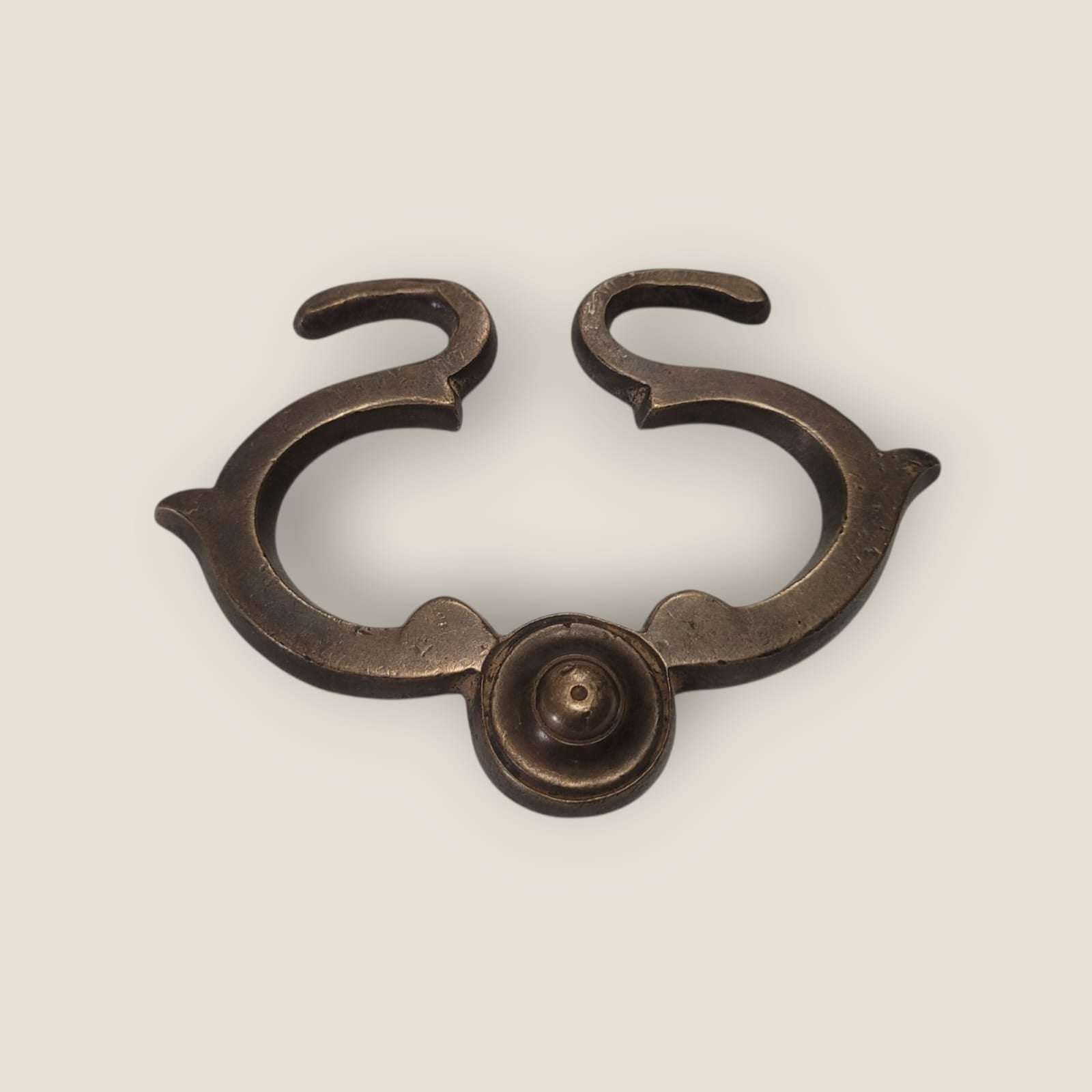 Tirador antiguo centrado en vista frontal, destacando su simetría y tornillo decorativo.