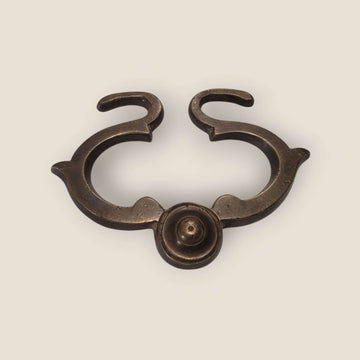 Tirador antiguo centrado en vista frontal, destacando su simetría y tornillo decorativo.