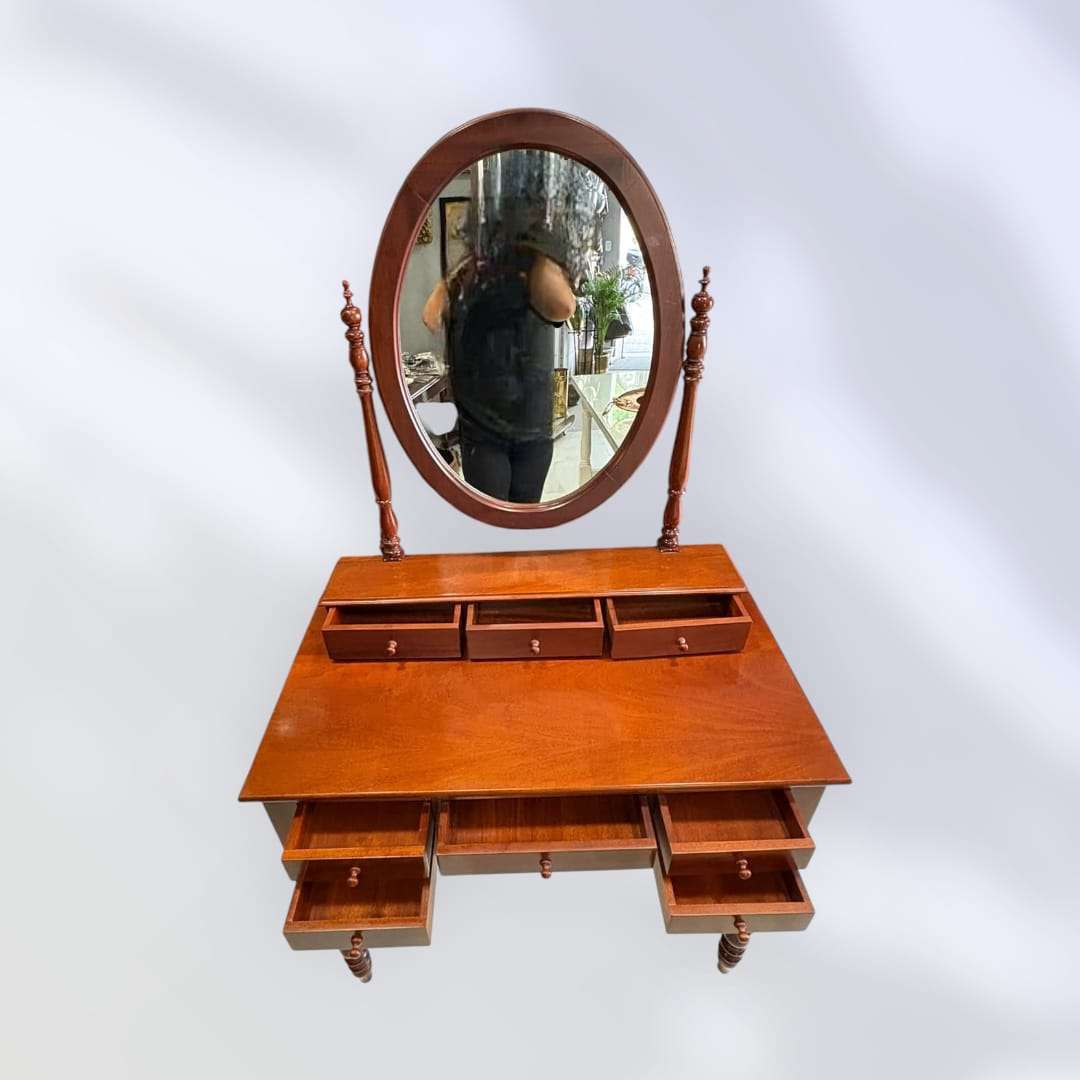 Tocador de caoba con espejo ovalado y cajones abiertos.