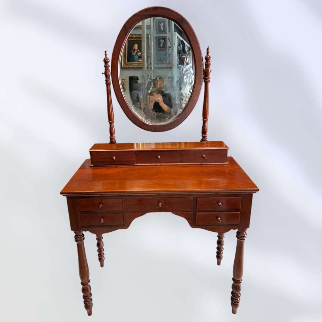 Tocador de caoba con espejo ovalado y cajones abiertos.