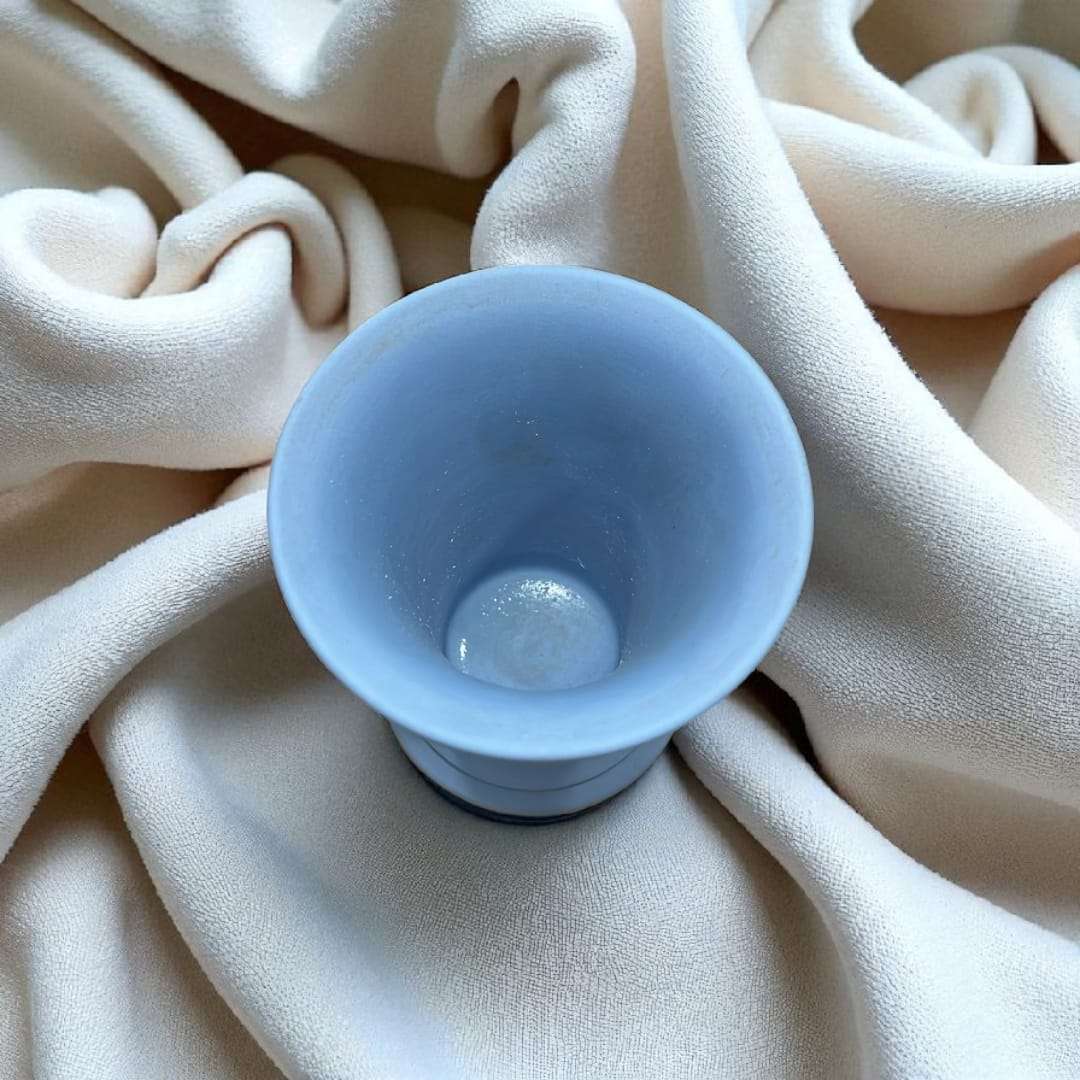 Jarrón Wedgwood azul jaspeado con relieve estilo clásico único sobre tela beige, ideal para decoración elegante en interiores.