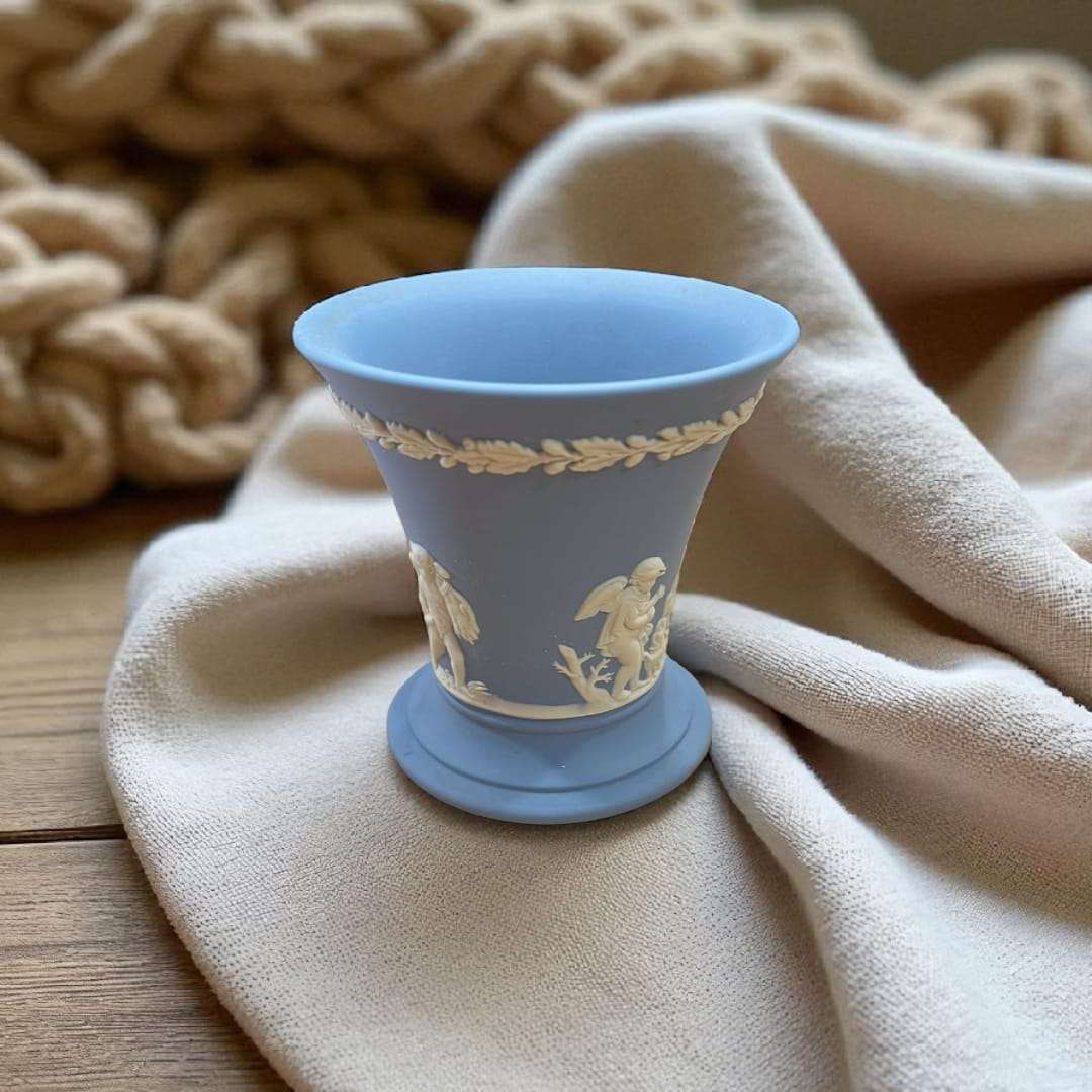 Jarrón Wedgwood azul jaspeado con relieve estilo clásico único sobre tela beige, ideal para decoración elegante en interiores.