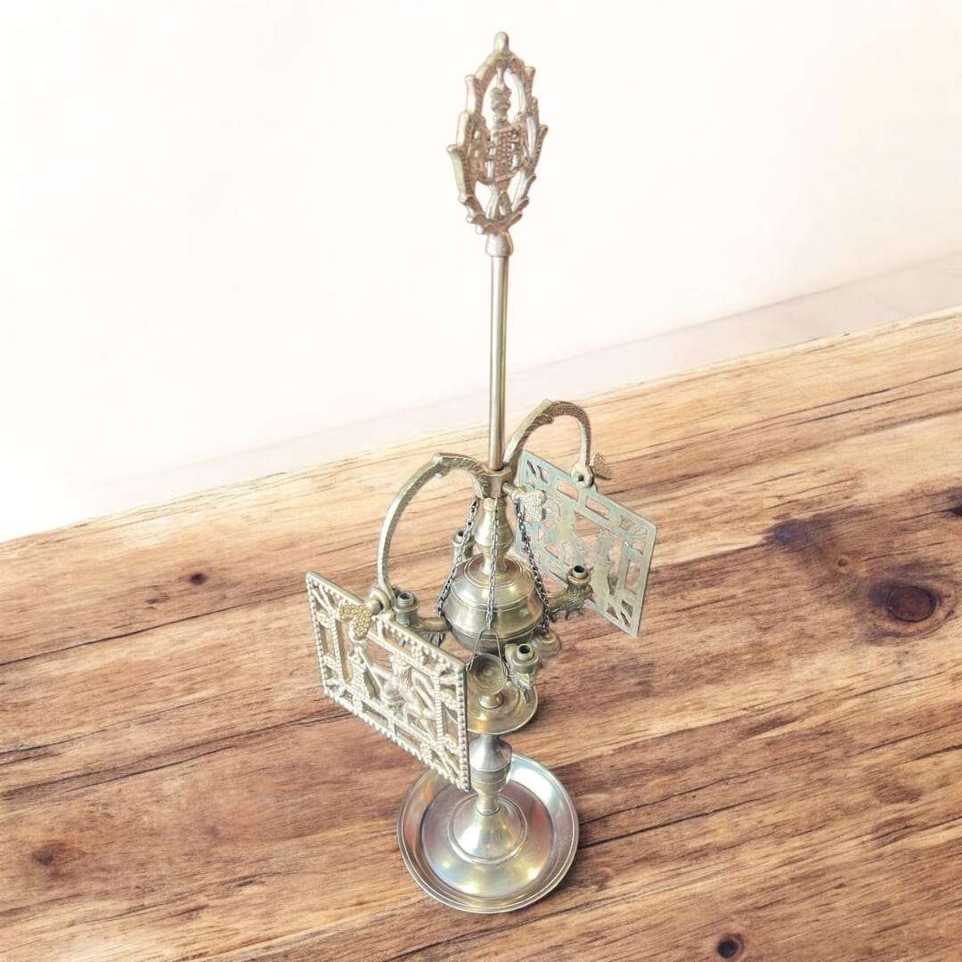 Velón de metal dorado con símbolos rituales colgantes y acabado artesanal. Pieza decorativa exclusiva para espacios místicos o vintage.