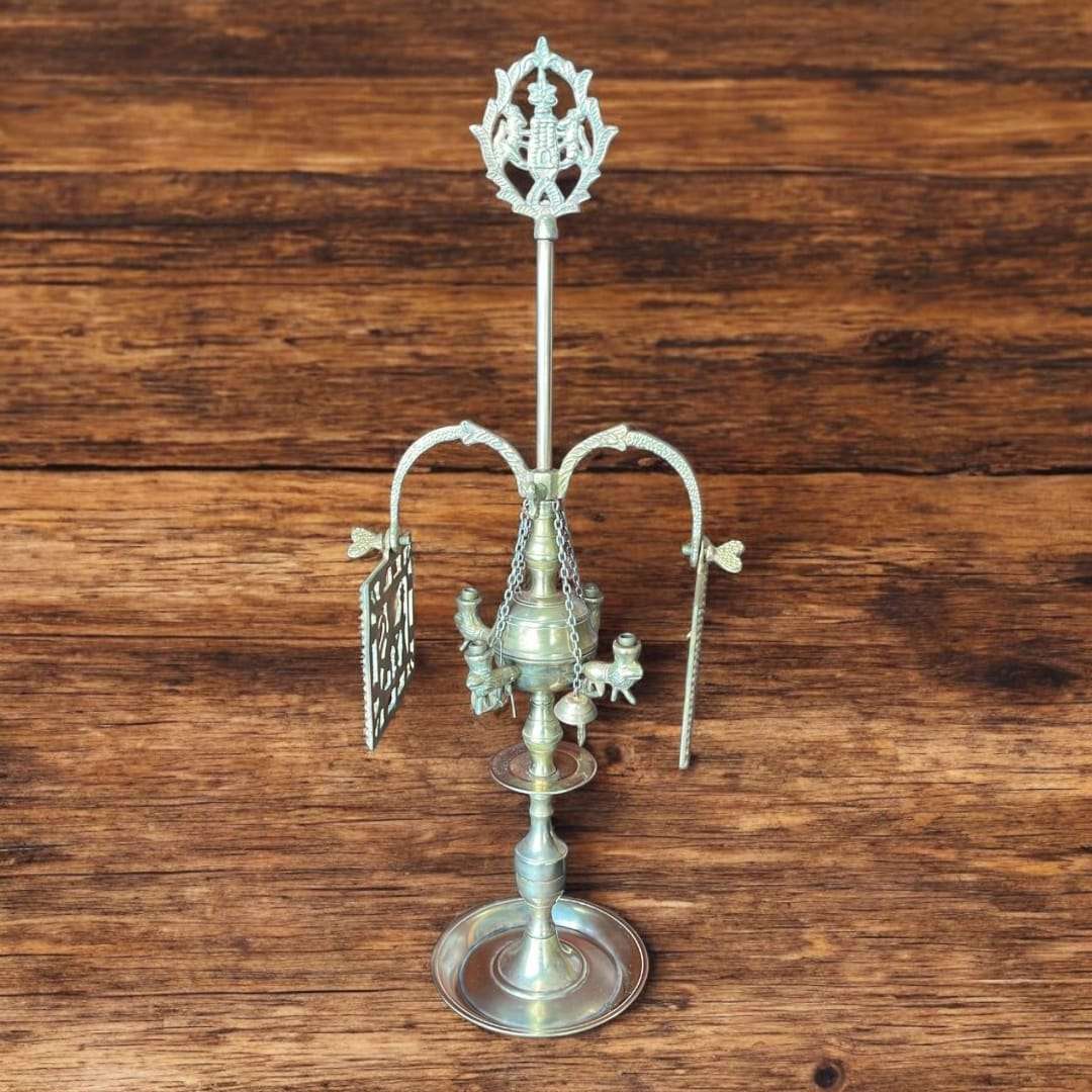 Velón de metal dorado decorativo con símbolos rituales únicos sobre mesa rústica. Ideal para decoración espiritual en hogar o altar.