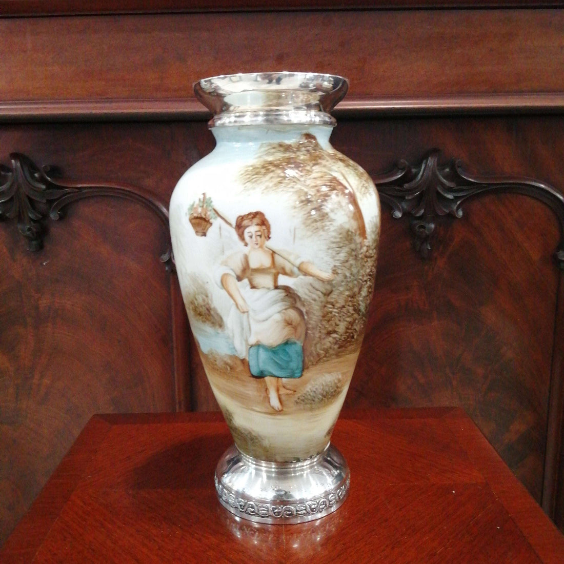 Jarrón de porcelana fina con plata de ley, decorado a mano con escena campestre y detalles clásicos, ideal para decorar interiores elegantes.